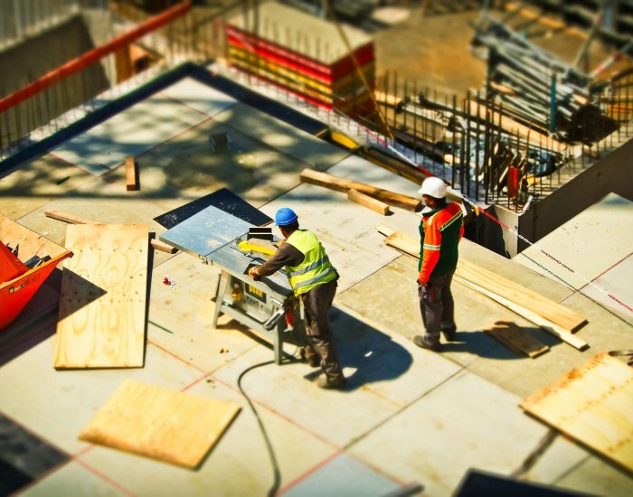 Construction workers engaging in tasks at an outdoor building site with safety hats and equipment.