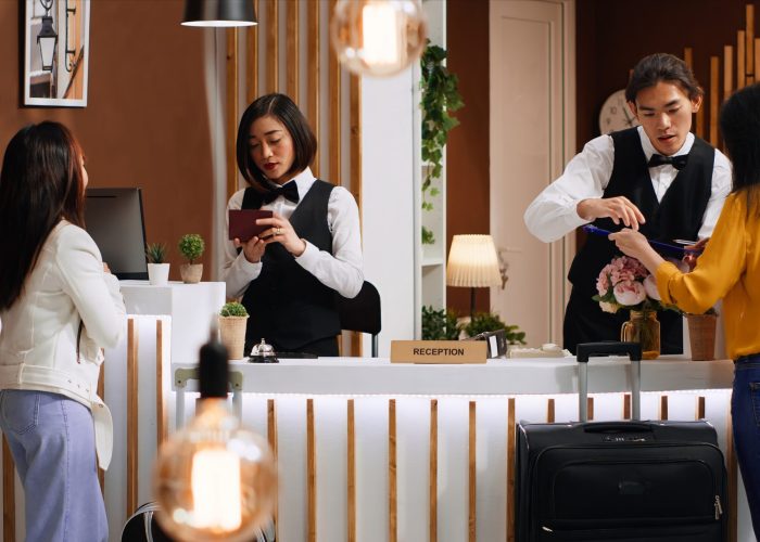 tourists going through check in process at hotel reception desk
